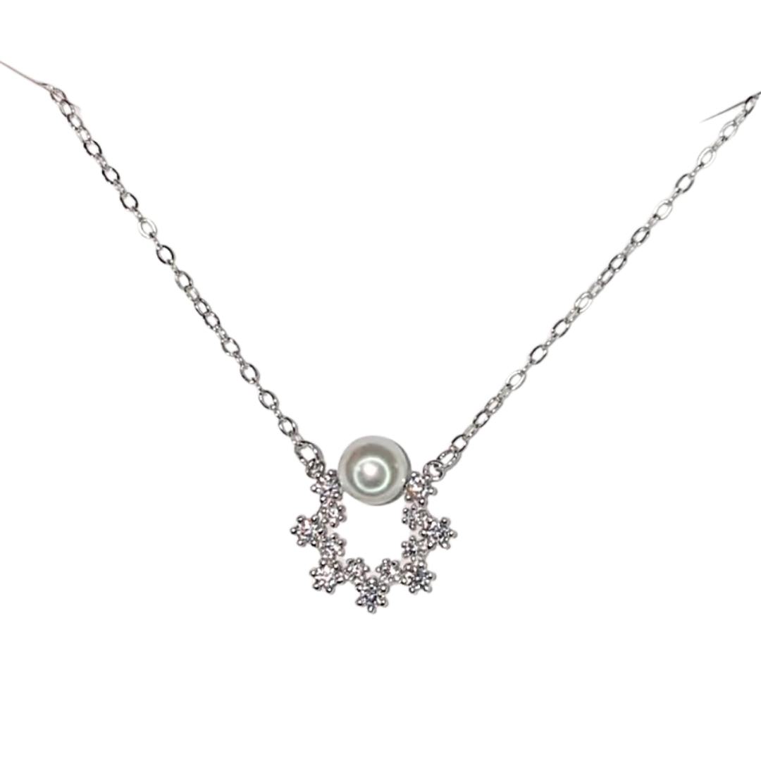 Silver necklace with CZ open circle design and pearl on top.