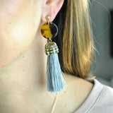 Earrings with large gray tassel adorned with mint beads connected to celluloid tortoise discs in ear.